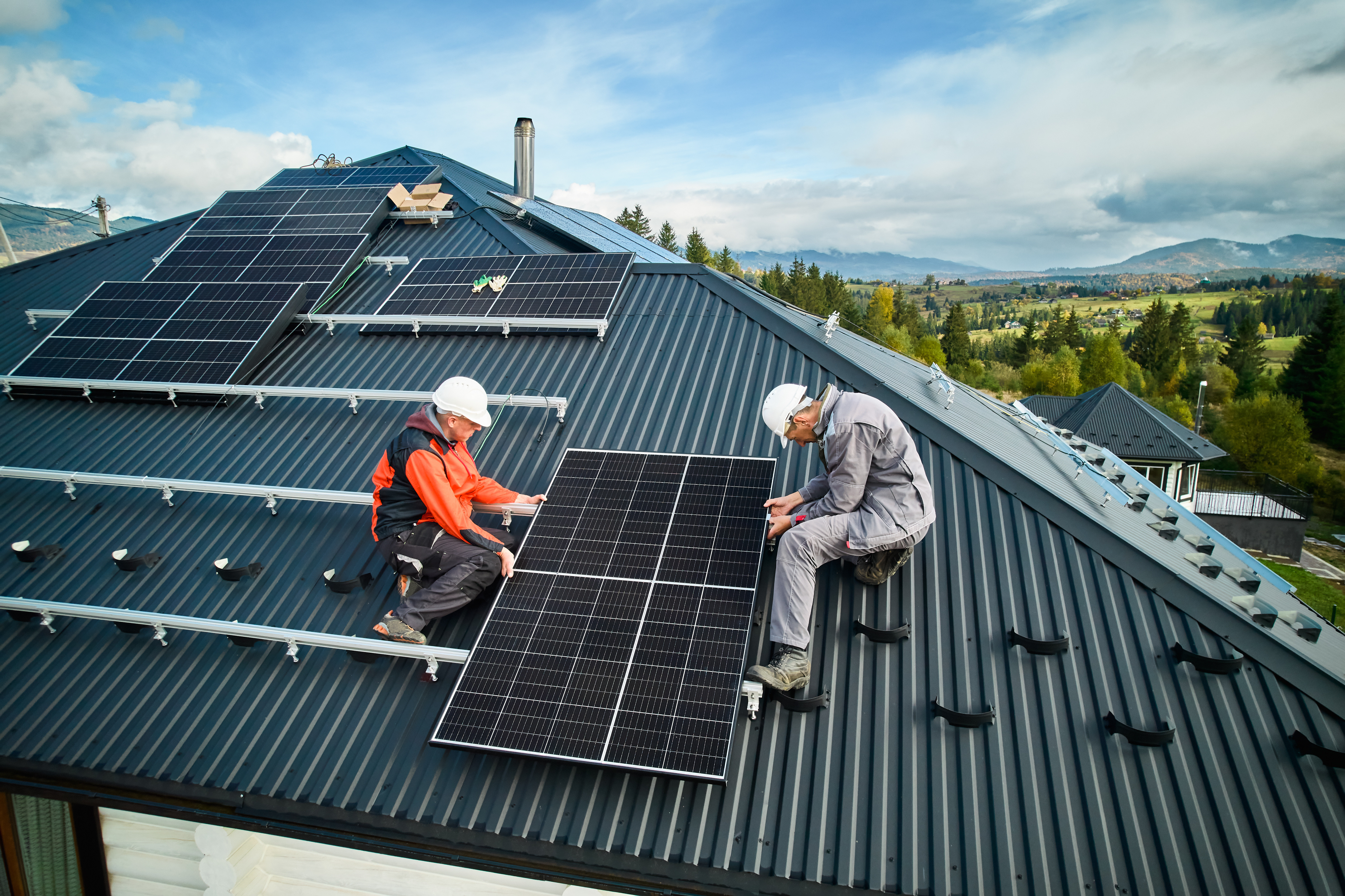 Two men installing solar panels on rooftop